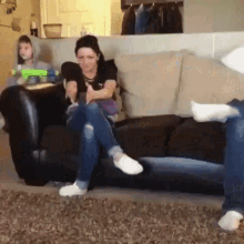 a woman is sitting on a couch with her legs crossed while a child looks on