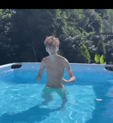 a shirtless man is standing in a swimming pool .