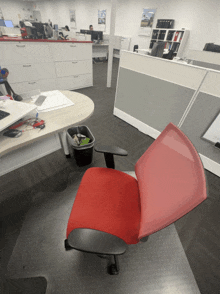 a red chair sits in the middle of an empty office