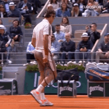 a tennis player is standing on a court holding a tennis racquet in front of a crowd of spectators .