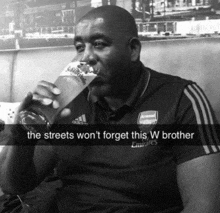 a man wearing an arsenal shirt is drinking from a glass