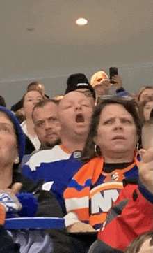 a man in a new york islanders jersey yawning in a crowd