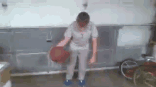 a man is holding a basketball in a garage with a bicycle in the background .