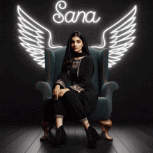 a woman in a black dress sits in a chair under a neon sign that says sana