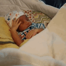 a baby is sleeping in a crib with a blanket and a hat .