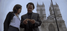 a man and a woman are standing in front of a building with a street sign that says broad sanctuary sw1