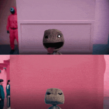 a man in a red suit is standing behind a pink wall next to a stuffed toy