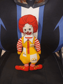 a stuffed mcdonald 's clown is sitting on a blue and white chair