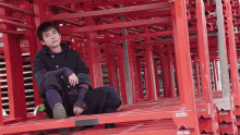 a man sits on a stack of red pallets with a label that says ' a ' on the bottom