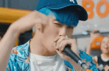 a man with blue hair is singing into a microphone while wearing a ny hat