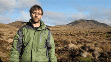 a man in a north face jacket stands in the middle of a field