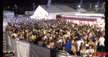 a crowd of people are gathered in front of a white tent with a sign that says paris on it