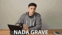 a man sitting at a table with a tablet and a cell phone and the words nada grave written on the screen