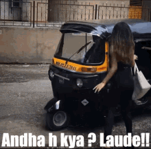 a woman is standing in front of an auto rickshaw with the words andha h kya laude on the bottom