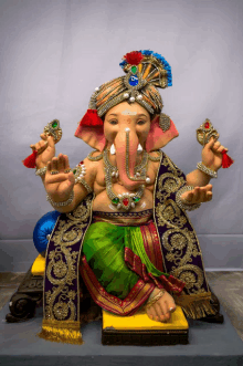 a statue of ganesha wearing a turban and a purple coat