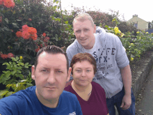 two men and a woman pose for a picture with one man wearing a shirt that says safe city