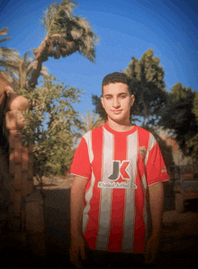 a boy wearing a red and white striped shirt that says khaled ruffali co.