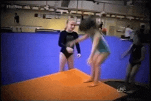 a group of young girls are doing a routine on a trampoline in a gym .