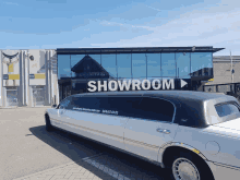 a white limousine parked in front of a building that says showroom