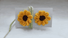 a pair of crocheted sunflowers are sitting on a card