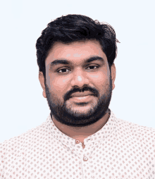 a man with a beard is wearing a white shirt with a pattern