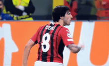 a soccer player wearing a red and black jersey with the number 8 on it