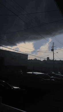 a dark cloudy sky over a parking lot with cars parked in front of a building