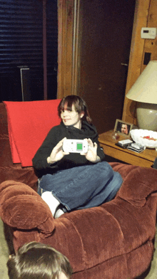 a woman sits in a chair holding a video game