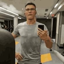 a man taking a picture of himself in a gym with his phone