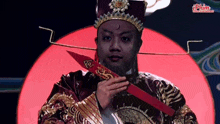 a man in a costume is holding a red sword with a chinese symbol on it