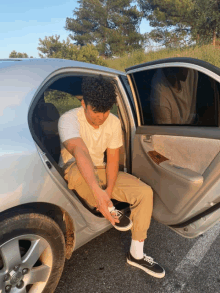 a young man sitting in the back of a silver car