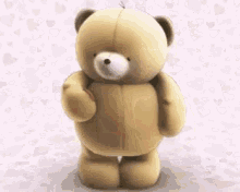 a teddy bear is standing in front of a pink background with hearts on it .