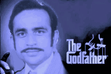 a man with glasses and a mustache is standing in front of a poster for the godfather