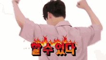 a man in a pink shirt is flexing his muscles in front of a white background with korean writing on it .