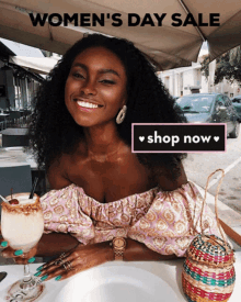 a woman sits at a table with a drink and a sign that says women 's day sale shop now