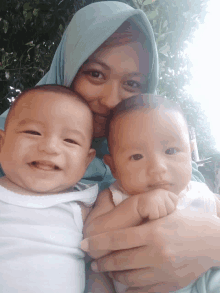 a woman is holding two babies in her arms