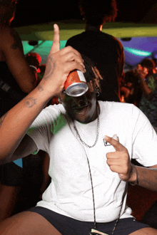 a man in a white t-shirt is holding a can over his head