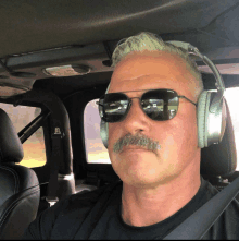 a man wearing headphones and sunglasses is sitting in a car