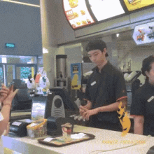 a man stands behind a counter at a fast food restaurant with a sign above him that says ' banner production '