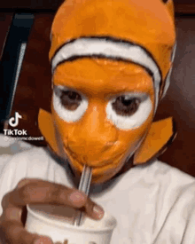 a person wearing a fish mask is drinking through a straw .