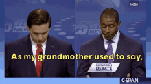 two men in suits and ties stand in front of a sign that says as my grandmother used to say