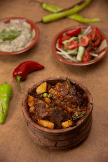 a wooden bowl filled with meat and vegetables next to a plate of vegetables