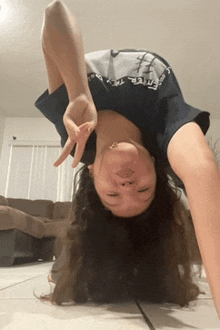 a woman in a nike shirt is doing a handstand on her head