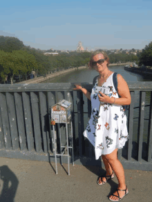 a woman in a white dress stands on a bridge next to a box that says " souvenirs " on it