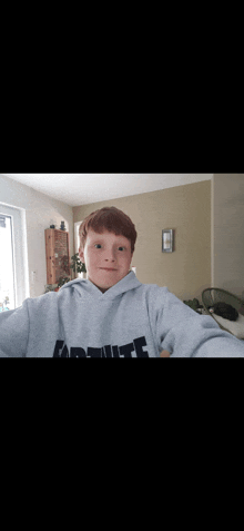 a young boy wearing a grey hoodie with the word assault on the front