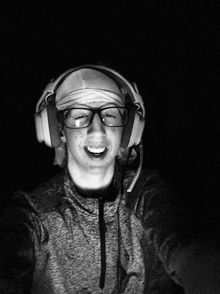 a man wearing headphones and glasses takes a selfie in the dark