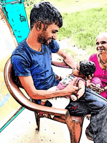 a man in a blue shirt is sitting in a chair holding a baby