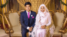 a man in a suit and tie and a woman in a hijab are posing for a picture