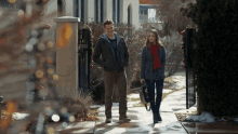 a man and woman are walking down a sidewalk in front of a building with a sign that says parking lot