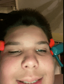 a close up of a young boy 's face with a toy gun on his forehead